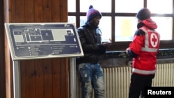 FILE - A Red Cross worker speaks with a migrant at the Bardonecchia railway station, northern Italy, Dec. 28, 2017.