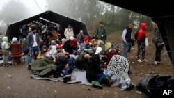 A group of migrants wait to cross a border line between Serbia and Croatia, near the village of Berkasovo, about 100 kilometers (62 miles) west of Belgrade, Serbia, Oct. 18, 2015. 