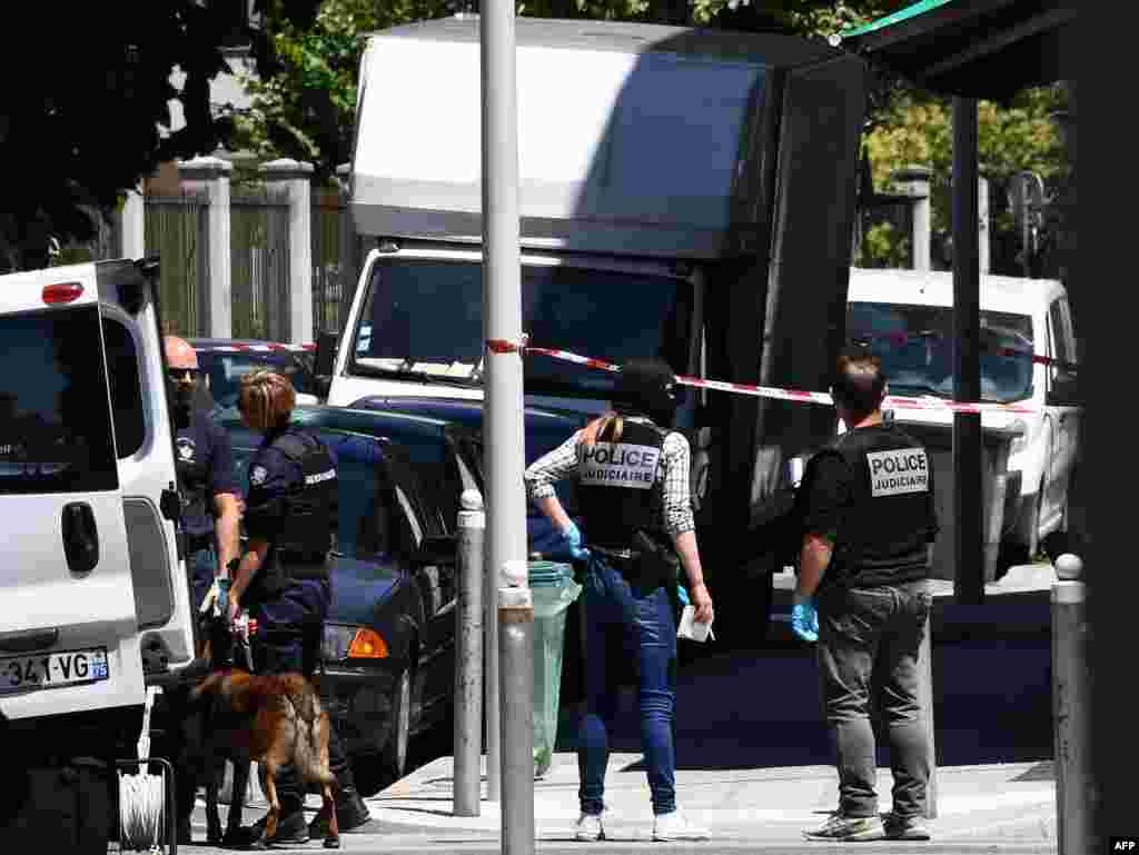 French police officers and French gendarmes stand near a truck in a street of Nice on July 15, 2016, near the building where the man who drove a truck into a crowd watching a fireworks display, the day before, reportedly lived.