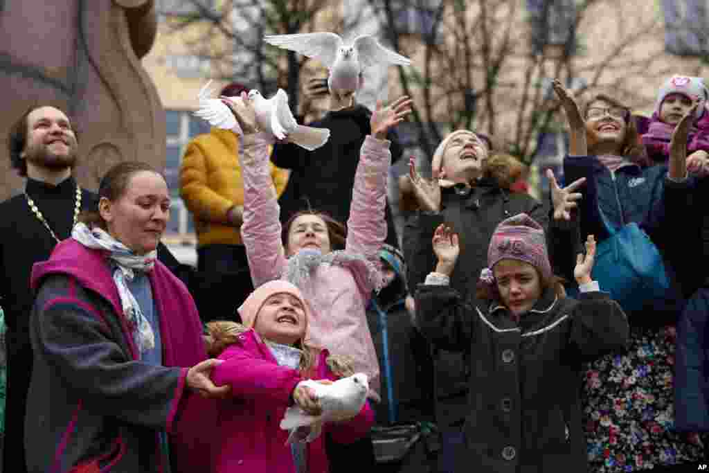 Children and their parents release birds celebrating the Annunciation on the eve of Orthodox Easter in front of the St. Tatiana Church in Moscow, Russia.