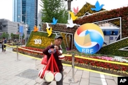 2019年4月19日，北京一带一路峰会论坛的宣传和装饰，一名卖鼓的男子走过。