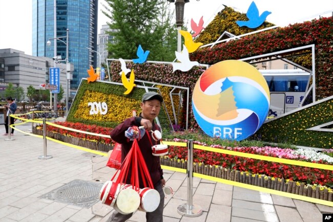 2019年4月19日，北京一带一路峰会论坛的宣传和装饰，一名卖鼓的男子走过。