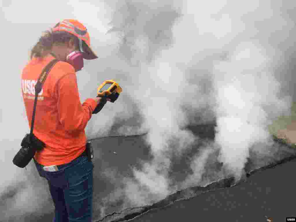 A geologist with the Hawaiian Volcano Observatory records a temperature of 103&deg; C (218&deg; F) at a crack along Nohea Street, Leilani Estates, Hawaii, May 9, 2018. The asphalt road was describes as &quot;mushy&quot; from the heat.