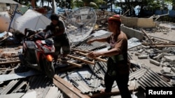 Warga mendorong sebuah motor dari bawah reruntuhan bangunan di Kecamatan Pemenang, Lombok (8/8).