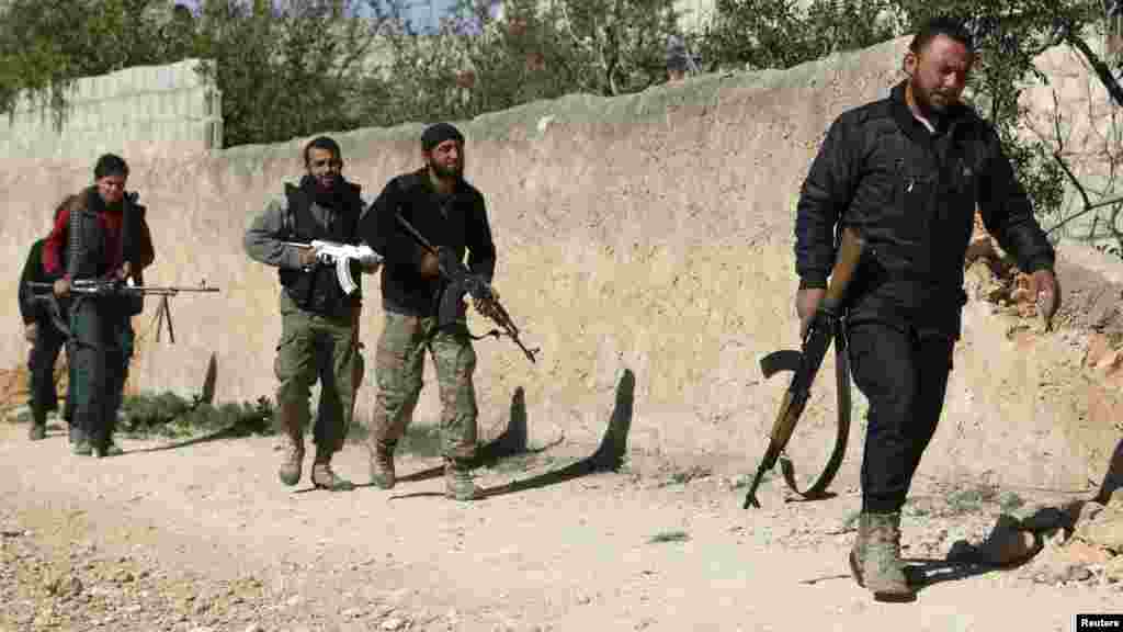 Free Syrian Army fighters walk with their weapons in Azaz village, north of Aleppo, March 30, 2014.