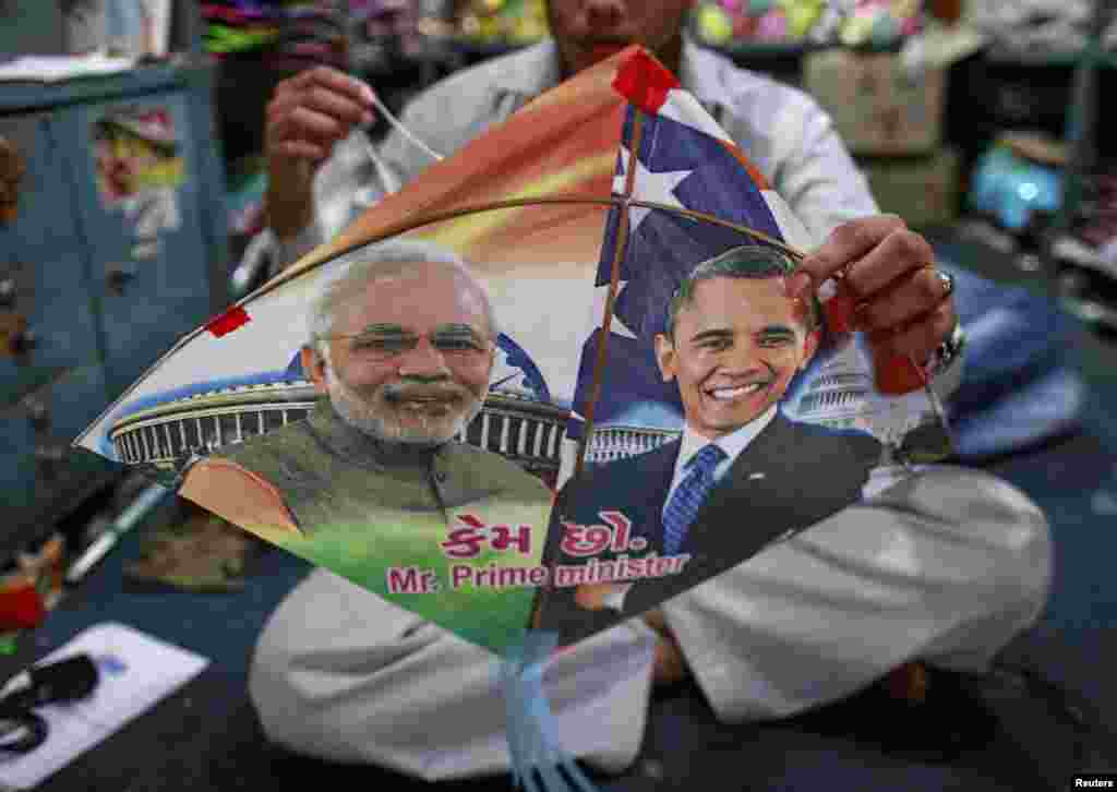Seorang pekerja mengikat benang pada sebuah layang-layang, yang bergambarkan potret Perdana Menteri India Narendra Modi (kiri) dan Presiden Amerika Barack Obama, sebelum kunjungan Obama, di Mumbai. &nbsp;