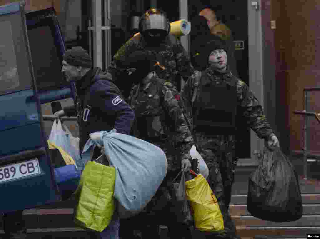 Members of the Ukrainian far-right radical group Right Sector leave their headquarters in Dnipro Hotel as police special forces stand guard, Kyiv, April 1, 2014.