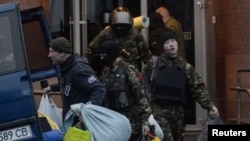 Members of the Ukrainian far-right radical group Right Sector leave their headquarters in Dnipro Hotel as police special forces stand guard, Kyiv, April 1, 2014.