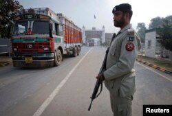 FILE - A paramilitary soldier stands guard as a truck crosses into Pakistan from India, at the Wagah border, Nov. 4, 2011.
