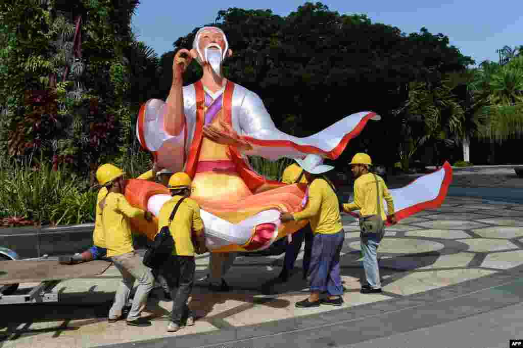 Workers carry a lantern figurine of matchmaker Yue Xia Lao Ren (Old Man under the moon) in preparation for the upcoming Mid-Autumn Festival at Garden by the Bay in Singapore.