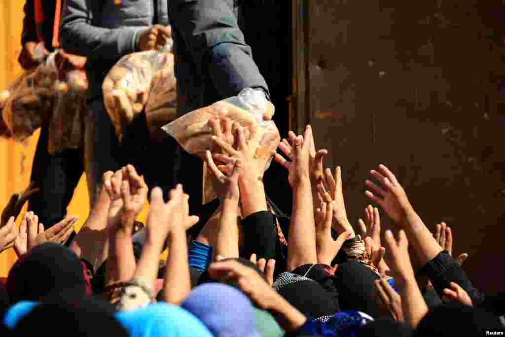 Displaced Iraqi people who fled from homes during a battle between Iraqi forces and Islamic State militants, receive bread at the Hammam al-Alil camp, south of Mosul.