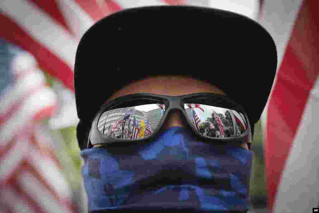 Banderas de Estados Unidos aparecen reflejadas en las gafas de un manifestante durante una marcha en Hong Kong, el domingo 8 de septiembre de 2019. (AP Foto/Kin Cheung)
