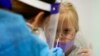 Karina Hoppmann, 7, gets a COVID-19 test before flying to Milan, Italy, with her family, at a testing center operated by Nomi Health inside Miami International Airport, Dec. 17, 2021, in Miami. 