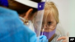 Karina Hoppmann, 7, gets a COVID-19 test before flying to Milan, Italy, with her family, at a testing center operated by Nomi Health inside Miami International Airport, Dec. 17, 2021, in Miami. 