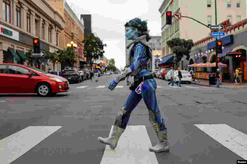 A women in costume walks across the downtown intersection during the spring night of the pop culture festival Comic Con International in San Diego, California, July 17, 2019.