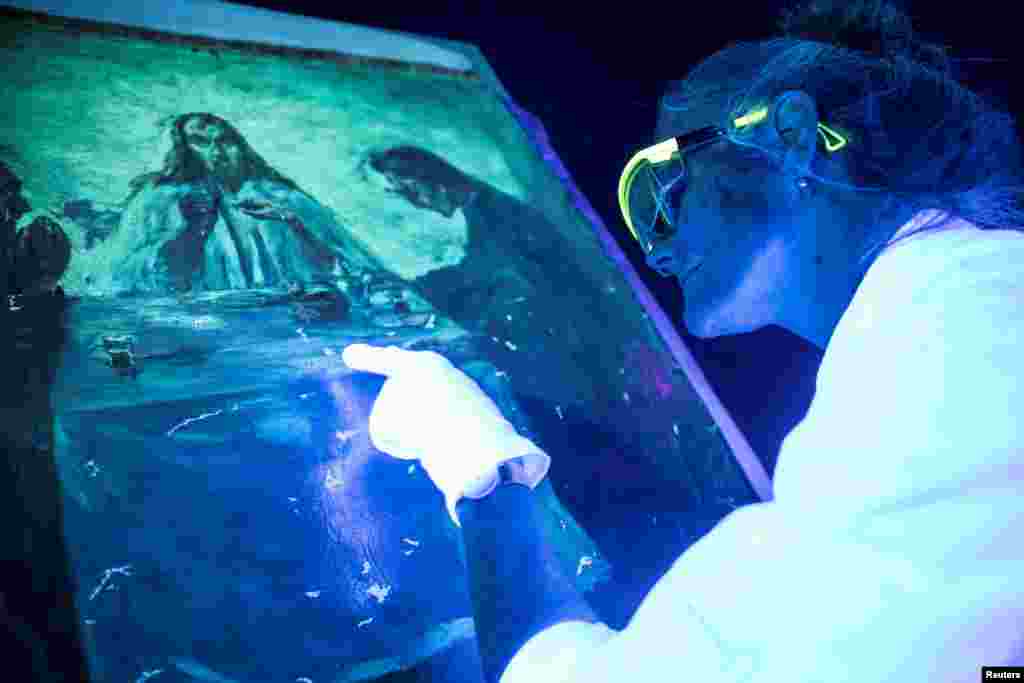 Conservation technician Mikala Bagge looks at Emil Nolde&rsquo;s painting &quot;Dinner in Emmaus&quot; in UV light to evaluate the damages after it has been stolen in 2014 and submerged in Jan. 2018, in Brede, Denmark.