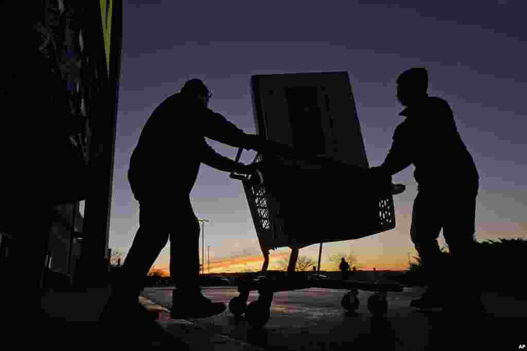 People transport a television to their car after shopping during a Black Friday sale in Overland Park, Kan.