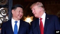 FILE - Chinese President Xi Jinping, left, smiles at U.S. President Donald Trump as they pose together with their wives for photographers before dinner at Mar-a-Lago in Palm Beach, Fla. 