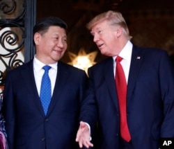 FILE - Chinese President Xi Jinping, left, smiles at U.S. President Donald Trump as they pose together with their wives for photographers before dinner at Mar-a-Lago in Palm Beach, Fla.