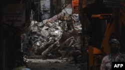Personel keamanan menutup lokasi setelah runtuhnya bangunan perumahan berlantai lima di Karachi, 9 Juni 2020. (Foto: Asif HASSAN / AFP)