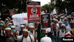 Demonstran membawa papan bertuliskan tuntutan atas penangkapan Gubernur Jakarta Basuki "Ahok" Tjahaja Purnama, yang dianggap menistakan agama, di Jakarta (2/12). (Reuters/Darren Whiteside)