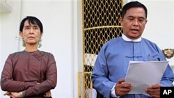 ဒေါ်အောင်ဆန်းစုကြည်နှင့် မြန်မာအစိုးရ ဝန်ကြီး ဦးအောင်ကြည်တို့ တွေ့ဆုံ ဆွေးနွေးအပြီး သတင်းထုတ်ပြန်ချက် ဖတ်ပြနေစဉ်။ ဇူလိုင်လ ၂၅၊ ၂၀၁၁။