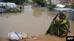 A woman living at a camp for the internally displaced sits on high ground above a flooded street on May 20, 2018 in Mogadishu after temporary shelters were inundated in Somalia's capital following heavy overnight rainfall. 