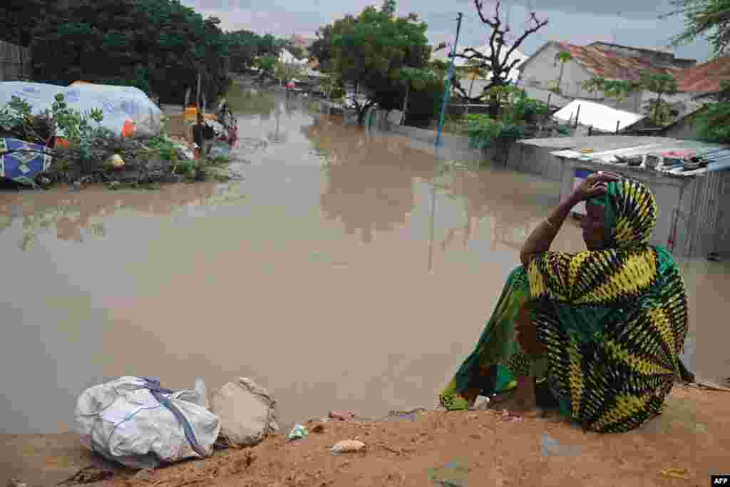 A woman living at a camp for the internally displaced sits on high ground above a flooded street in Mogadishu, after temporary shelters were inundated in Somalia&#39;s capital following heavy overnight rainfall.