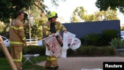 Một lính cứu hỏa đem các túi đựng chất liệu nguy hiểm vào lãnh sự quán Hàn Quốc ở Melboune hôm 9/1. Cảnh sát Liên bang Úc đang điều tra các bưu kiện khả nghi được gửi tới các phái bộ ngoại giao ở nước này.