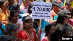 FILE - A demonstrator holds a placard in Mumbai in a protest targeting Sri Lanka's President Mahinda Rajapaksa and alleged war crimes against Tamil civilians in his country, March 20, 2013. 