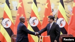 FILE - Ugandan President Yoweri Kaguta Museveni, left, shakes hands with Chinese President Xi Jinping during a signing ceremony in the Great Hall of the People in Beijing, March 31, 2015.