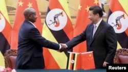 FILE - Ugandan President Yoweri Kaguta Museveni, left, shakes hands with Chinese President Xi Jinping during a signing ceremony in the Great Hall of the People in Beijing, March 31, 2015.