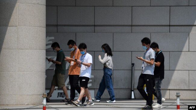 北京一群青年边走路边看手机。(2020年7月6日)