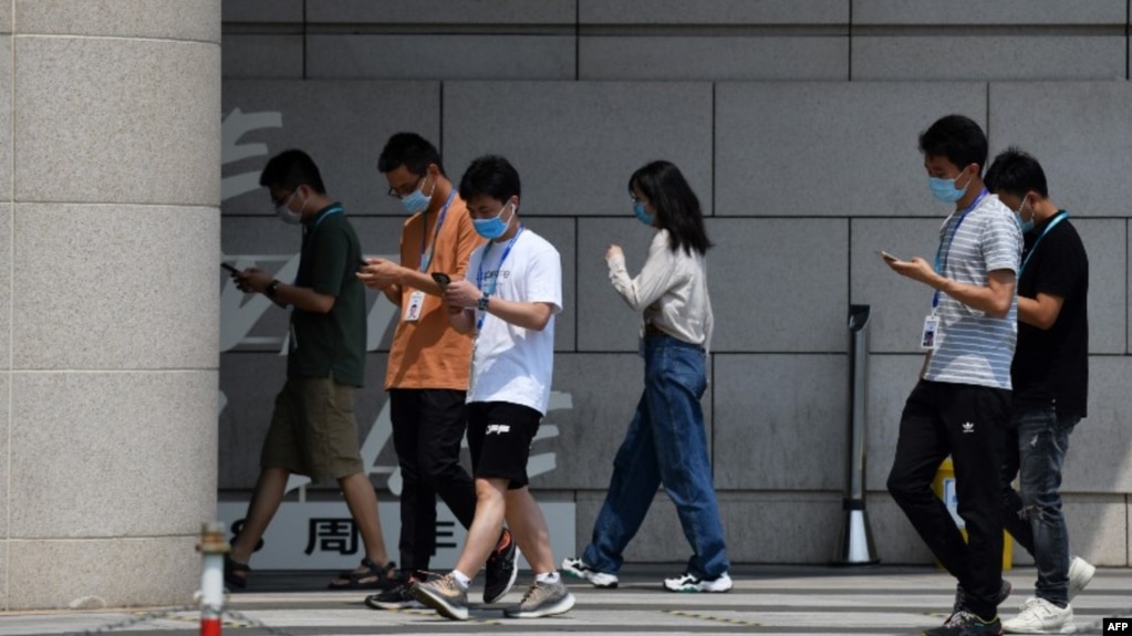 在北京的字节跳动公司雇员边走路边看手机。（2020年7月6日）(photo:VOA)