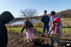 Ali Patan, 7, right, shovels dirt while looking for worms with his brothers, Sala and Maiwan, and cousins Laiba and her brother, Haiwad, while visiting the farm of Caroline Clarin in Dalton, Minn., Oct. 30, 2021.