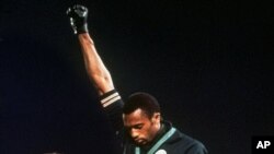 Tommie Smith, médaille d'or du 200m, lève le poing pour protester contre les inégalités raciales aux USA lors de l'hymne américain. 