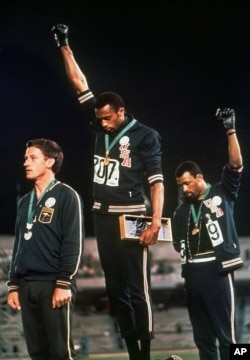 FILE - U.S. athletes Tommie Smith, center, and John Carlos raise their black-gloved firsts in racial protest during the playing of "The Star-Spangled Banner" after Smith received the gold and Carlos the bronze medal in the 200-meter run at the Summer Olympic Games in Mexico City, Oct. 16, 1968.