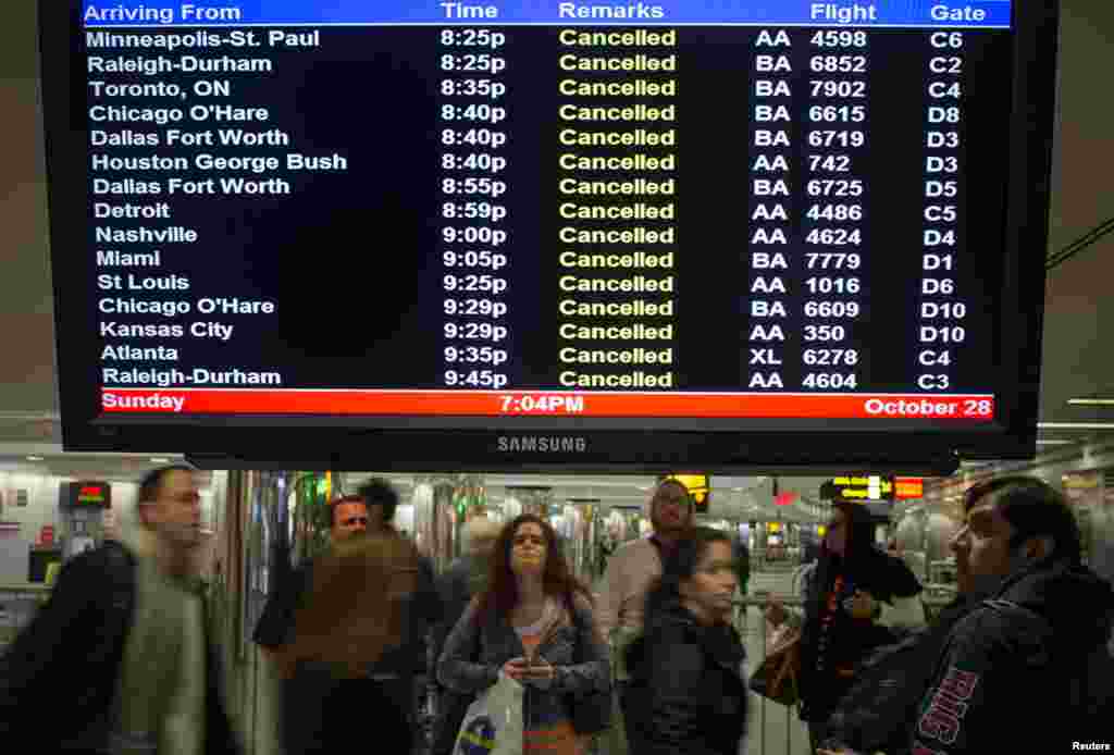 Travelers surround a flight monitor showing cancelled flights at LaGuardia airport in New York October 28, 2012.