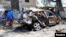 A Somali woman looks at the wreckage of a vehicle near the scene of an explosion in Mogadishu, Somalia, March 7, 2019. 