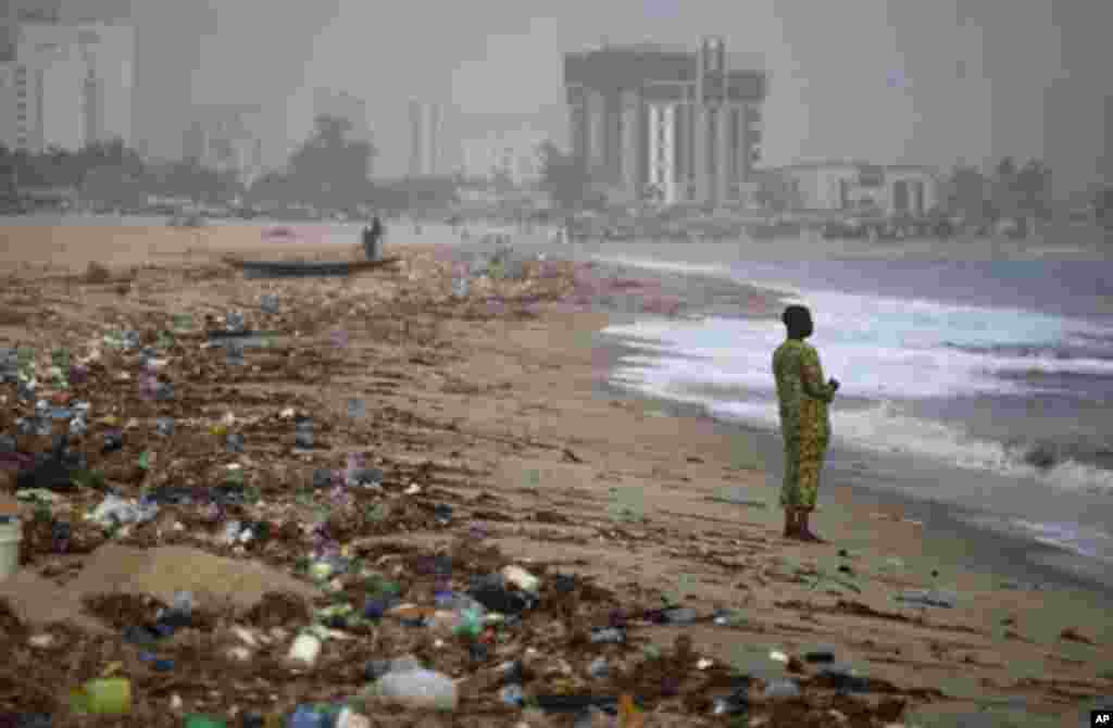 A man stands on the shore of Bar Beach, awash with rubbish and waste, in Lagos December 15, 2011. REUTERS/Akintunde Akinleye (NIGERIA - Tags: ENVIRONMENT SOCIETY)