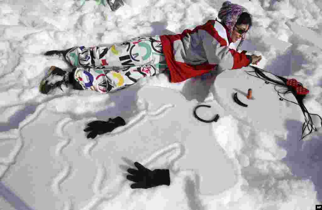 Seorang perempuan Iran membuat &quot;snowwoman&quot; pada kompetisi di Dizin di sebelah utara ibukota Iran, Tehran. Sekitar 600 warga Iran berpartisipasi dalam festival salju yang diselenggarakan oleh Federasi Ski Iran di resor ski Dizin. 