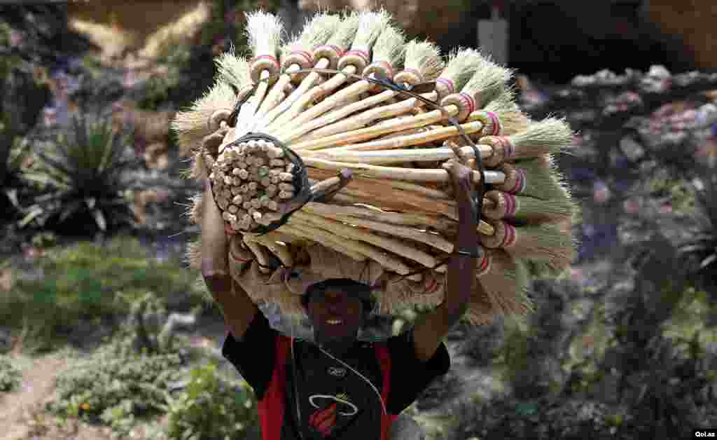 A trader carries sweeping brooms for sale along the streets of Madagascar's capital Antananarivo.
