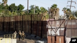 Infantes de marina patrullan una valla fronteriza que separa a Tijuana, México, en el fondo, y San Diego, cerca del cruce fronterizo de San Ysidro, en California. (AP Foto/Gregory Bull).