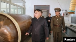 지난해 8월 북한의 김정은 국무위원장이 국방과학원 화학재료연구소 시찰 사진에 갈색의 원통 물체 옆에 서 있다. 