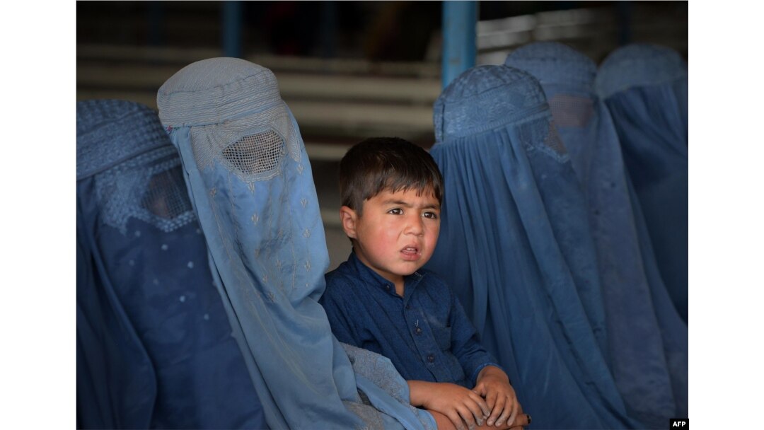 FILE - Afghan refugee families wait to be registered at the United Nations High Commissioner for Refugees (UNHCR) repatriation center on the outskirts of Peshawar, April 27, 2017.