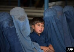 FILE - Afghan refugee families wait to be registered at the United Nations High Commissioner for Refugees (UNHCR) repatriation center on the outskirts of Peshawar, April 27, 2017.