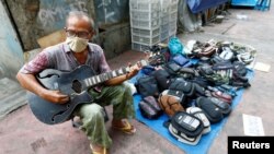 Seorang penjaja dagangan bermain gitar sambil menunggu pembeli di pinggir jalan di tengah pandemi Covid-19 di Jakarta (foto: ilustrasi). 