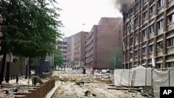 In this video image taken from television, smoke is seen billowing from a damaged building as debris is strewn across the street after an explosion in Oslo, Norway, Friday, July 22, 2011