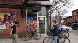 FILE - High school students hang out on a Brooklyn street corner, Friday, March 20, 2020 in New York. The city's public schools are closed due to the coronavirus. (AP Photo/Mark Lennihan)