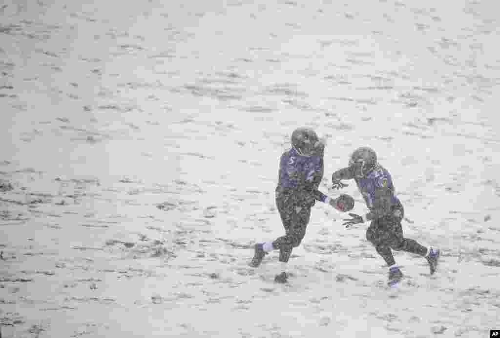 Baltimore Ravens quarterback Joe Flacco, left, hands the ball off to running back Ray Rice as snow falls in the first half of an NFL football game against the Minnesota Vikings in Baltimore, Maryland, USA. 